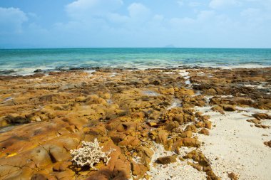 Okyanusta düşük gelgit zamanında tropikal adanın kıyıları. Masmavi su, sualtı taşları ve beyaz mercan kumu ile Seascape. Tayland. Andaman Denizi.