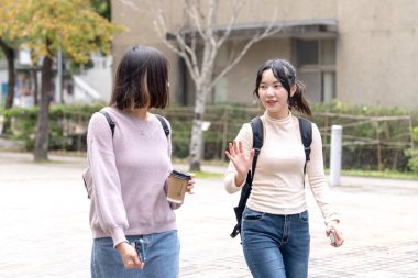 Tayvanlı iki genç üniversite öğrencisi Tayvan, Tayvan 'daki üniversite kampüsünde mutlu mesut konuşuyorlar.. 