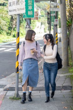 Tayvanlı iki genç üniversite öğrencisi Tayvan, Taipei 'de bir yolda mutlu bir şekilde yürüyorlar..