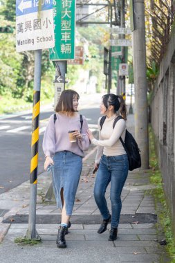 Tayvanlı iki genç üniversite öğrencisi Tayvan, Taipei 'de bir yolda mutlu bir şekilde yürüyorlar..