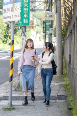 Tayvanlı iki genç üniversite öğrencisi Tayvan, Taipei 'de bir yolda mutlu bir şekilde yürüyorlar..