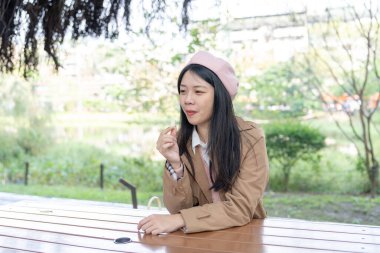 Tayvan 'ın Taipei kentindeki bir parkta 20' li yaşlarda genç bir Tayvanlı kadın bankta oturup şeker yiyor.