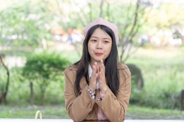 Tayvan 'da Tayvan' da bir parkta bankta oturan 20 'li yaşlarında gülümseyen genç bir Tayvanlı kadın.