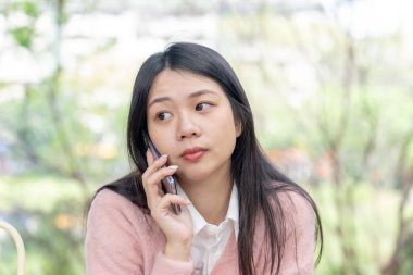Tayvan 'ın Taipei şehrinde bir parkta 20' li yaşlarda genç bir Tayvanlı kadın bir bankta oturuyor ve akıllı telefonuyla konuşuyor.