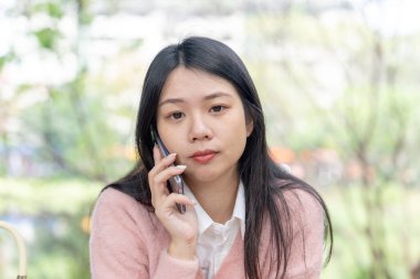 Tayvan 'ın Taipei şehrinde bir parkta 20' li yaşlarda genç bir Tayvanlı kadın bir bankta oturuyor ve akıllı telefonuyla konuşuyor.