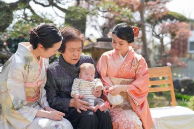 Bir grup kadın bir bankta oturuyor, içlerinden biri bebeği tutuyor. Huzurlu ve iç açıcı bir sahne. Kadınlar birbirlerinin arkadaşlığından ve bebeğin varlığından keyif alıyor.