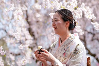 A woman is smiling while holding a cupcake in her hand. Concept of happiness and enjoyment, as the woman is savoring the moment and the delicious treat