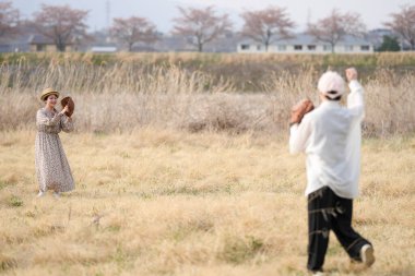 Bir adam ve bir kadın bir tarlada beyzbol oynuyorlar. Kadının elinde beyzbol eldiveni ve adamın elinde beyzbol sopası var. Sahne huzurlu ve rahat.