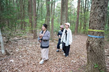 Bir grup insan bir ormanda yürüyor, içlerinden biri bebek tutuyor. Sahne huzurlu ve huzurlu, çünkü grup doğadaki zamanlarından zevk alıyor gibi görünüyor.