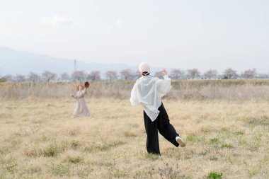 Beyaz gömlekli ve siyah pantolonlu bir adam tarlada koşuyor. Yakınlarda bir kadın var. Sahne sakin ve sakin, erkek ve kadın dışarıda eğleniyor.