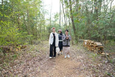 Ormanda yürüyen üç kadın. İçlerinden biri beyaz gömlek giyiyor.