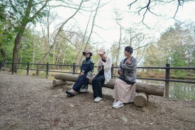 Parkta bir bankta üç kadın oturuyor. İçlerinden biri bir bebek tutuyor. Manzara huzurlu ve rahatlatıcı.