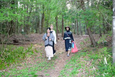 Üç kadın bir ormanda yürüyor, biri bebek taşıyor. Manzara huzurlu ve huzurlu, kadınlar doğada vakit geçirmekten hoşlanıyor.