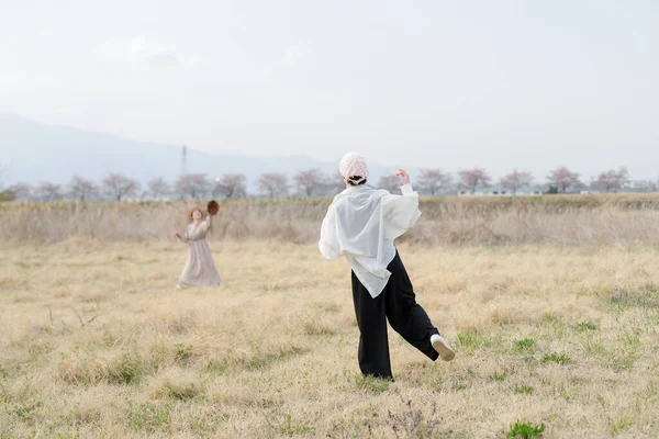 Beyaz gömlekli ve siyah pantolonlu bir adam tarlada koşuyor. Yakınlarda bir kadın var. Sahne sakin ve sakin, erkek ve kadın dışarıda eğleniyor.