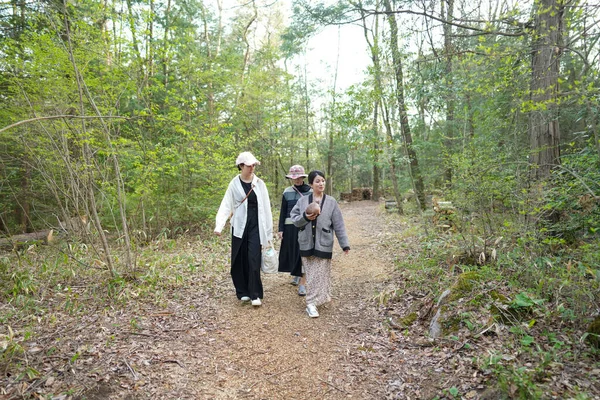 Ormanda yürüyen üç kadın. İçlerinden biri beyaz gömlek giyiyor.