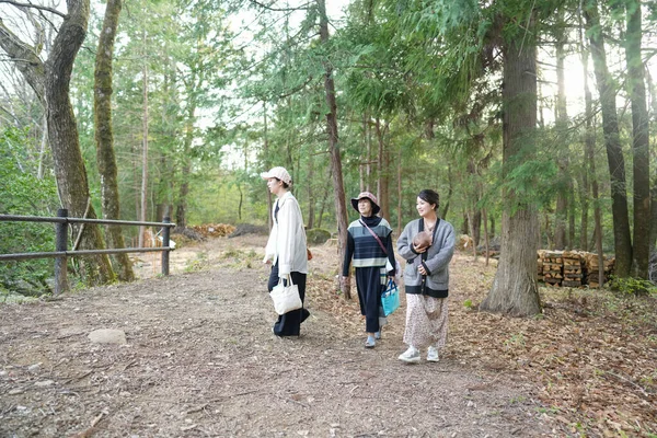 Üç kadın bir ormanda yürüyor, biri bebek taşıyor. Atmosfer sakin ve sakin, ayak altında çatırdayan yaprakların sesiyle.