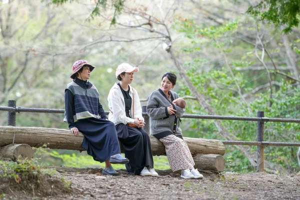 Ormandaki bir kütükte üç kadın oturuyor. İçlerinden biri bir bebek tutuyor.