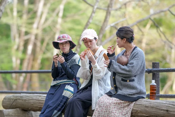 Üç kadın bir bankta oturuyor, yiyor ve içiyor. İçlerinden biri bir bebek tutuyor. Sahne rahat ve rahat, kadınlar birlikte huzurlu bir ortamda vakit geçiriyorlar.