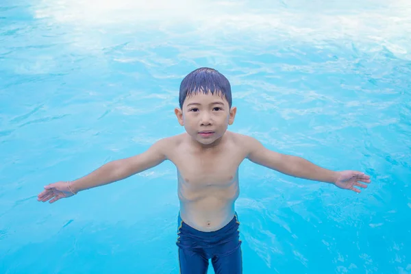 Asiático chico extendió sus brazos jugando en la piscina — Foto de Stock
