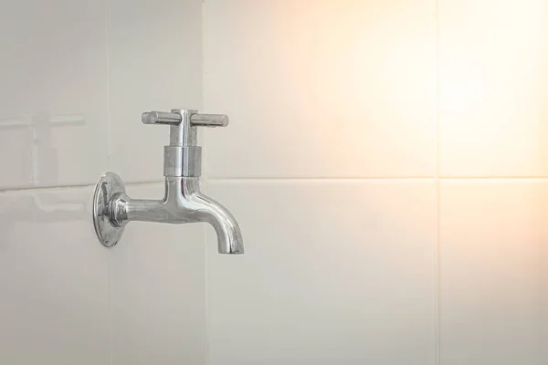 Silver metal faucet on white tile floor — Stock Photo, Image