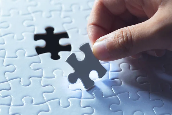Ręka trzyma kawałek pustego jigsaw puzzle — Zdjęcie stockowe