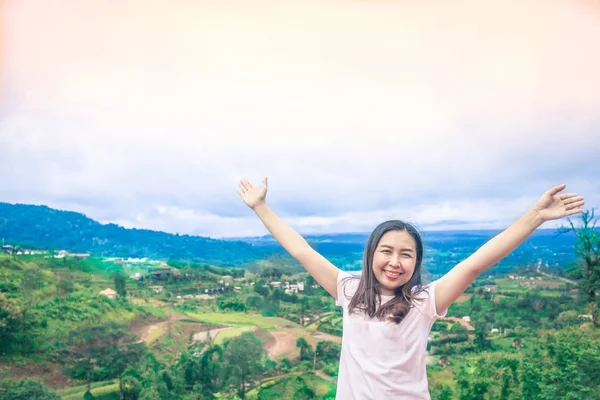 Happy Asian woman stands her arms on a beautiful view of the mou ロイヤリティフリーのストック画像