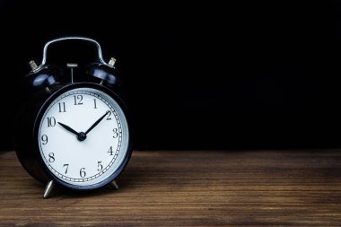 Ahşap masa üzerinde siyah arkaplan izole nesne sanatı ile geri alarm saati
