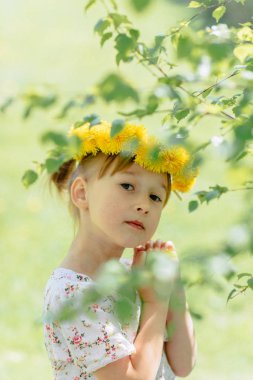 küçük sevimli beyaz kız bahçede karahindiba çelenk ile