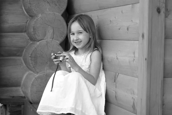 Kleines Mädchen Sitzt Mit Kamera Neben Holzhaus — Stockfoto