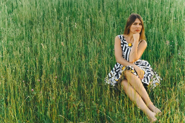 年轻女子穿着礼服坐在绿草 — 图库照片