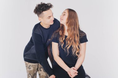 Stüdyoda beyaz arka planda poz veren genç bir çift. 