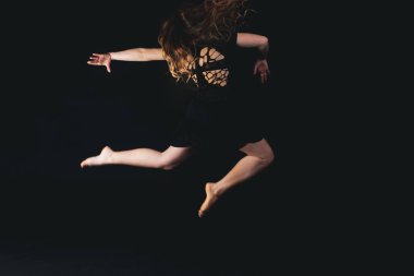 Stüdyoda siyah arka planda poz veren genç bir kız. 