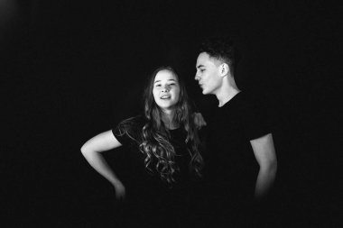 Stüdyoda siyah arka planda poz veren genç bir çift. 