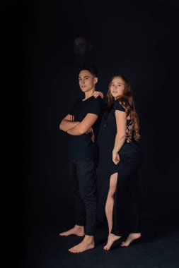 Stüdyoda siyah arka planda poz veren genç bir çift. 