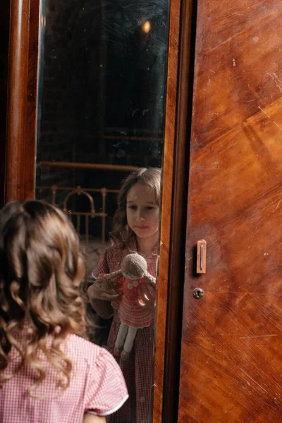 Маленькая Девочка Держит Куклу Старой Комнате Смотрит Зеркало — стоковое фото