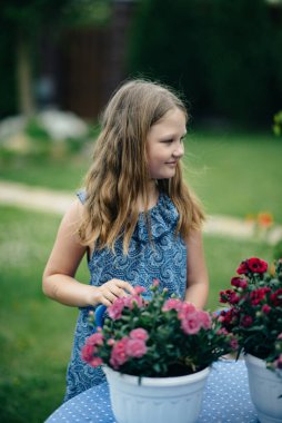 Bahçede çiçekleri olan küçük güzel bir kız