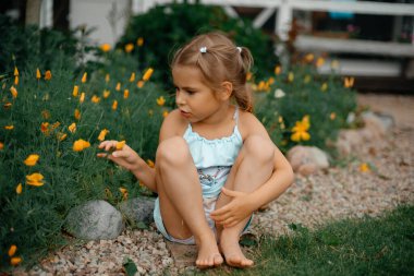 Yazın açık havada elbisesiyle gezen küçük bir kız arka planda çiçekler var. Hayata sağlıklı bir bakış açısı. Memlekette mutlu bir bebek. Uzayı kopyala Tonlama.