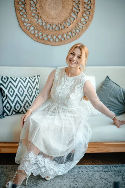 在一个舒适的客厅里 一个穿着白色长裙的女孩坐在沙发上欣赏 新娘子快乐婚礼当天 时尚与时尚的概念 复制空间 Toning案 — 图库照片