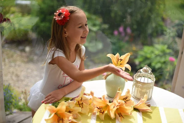 Liten Flicka Vid Bordet Terrassen Vackra Gula Liljor Ligger Bordet — Stockfoto