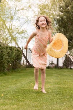 Yazın kırsalda koşan sarı elbiseli küçük bir kız. Çocuk yarım at gibi koşuyor. Kısa parlak kıvırcık saçlı. Çocukların gücü ve moda kavramı. Tasasız çocukluk.