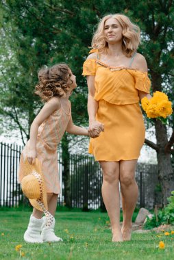 Elbiseli anne ve kızı çimenlikteki yazlık evde dinleniyor ve keyif alıyorlar. Yaz tatili.