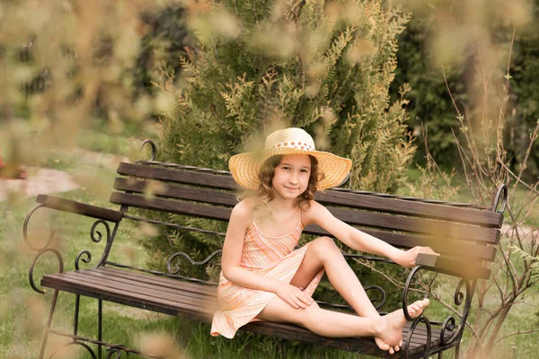 머리에 모자를 드레스를 소녀가 별장에 벤치에 있습니다 곱슬곱슬 곱슬머리 어린이의 — 스톡 사진