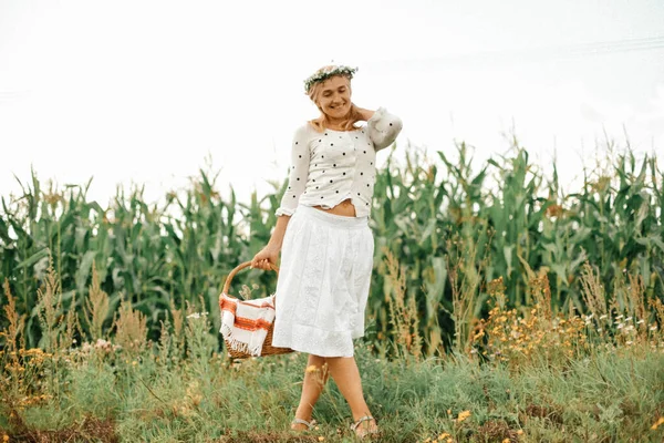 迷人的金发姑娘穿着白色的连衣裙 手里拿着篮子 背景是一片玉米地 快乐和有趣的概念 夏日晴天 — 图库照片
