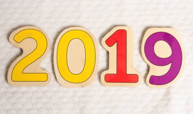 Eski beyaz zemin üzerine ahşap numarası 2019. Beyaz doku masaya yeni yıl 2019 sayısını oluşturan oyma ahşap basamak. Mutlu yeni yıl 2019. Renkli (sarı, kırmızı, mor).