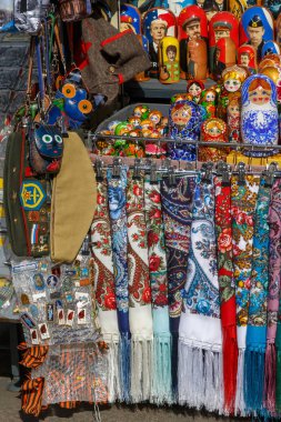 Renkli şallar, eşarplar, boyalı matryoshkas, dekoratif küçük çantalar, çantalar ve askeri şapka gibi Rus Hatıra Eşyası tezgahın üzerine yalan ve yabancı turistler için bekleyin