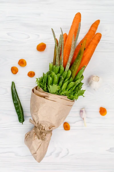 A beautiful bouquet of vegetables lies on a white wooden table as a gift to a vegetarian