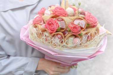Kız onun elinde bir gül ve çeşitli tatlılar pembe çiçek hediye olarak oluşan güzel bir buket tutar.
