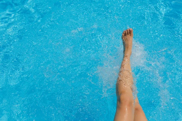 Nice pretty female feet, water splashes and turquoise pool water
