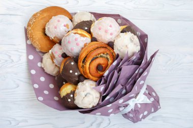 Buket farklı lezzetli çörekler ve çörek yapılmış bir beyaz tahta masada yatıyor