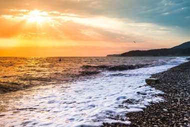 Denizin kenarında rüzgarlı havalarda mistik turuncu günbatımı